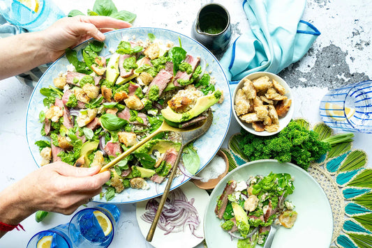 Hands serving up salad with beef
