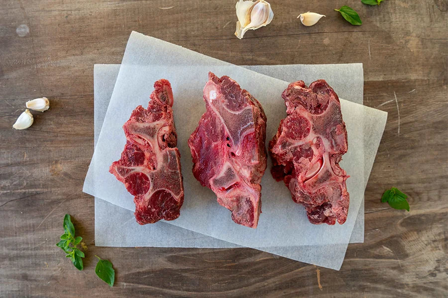Three Angus beef bones with herbs and garlic cloves