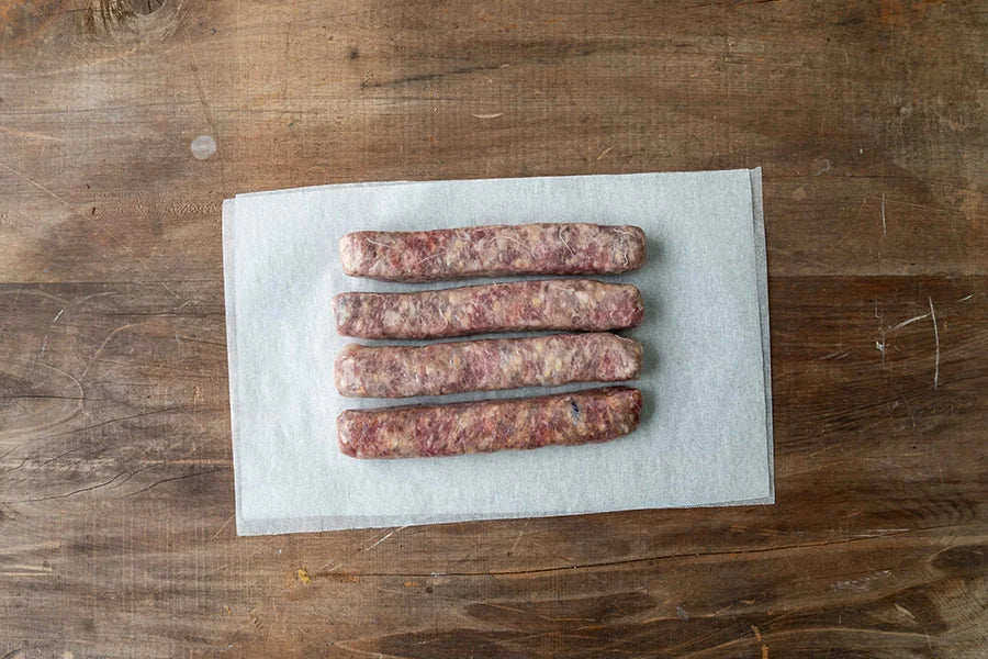 four pork sausages on baking paper