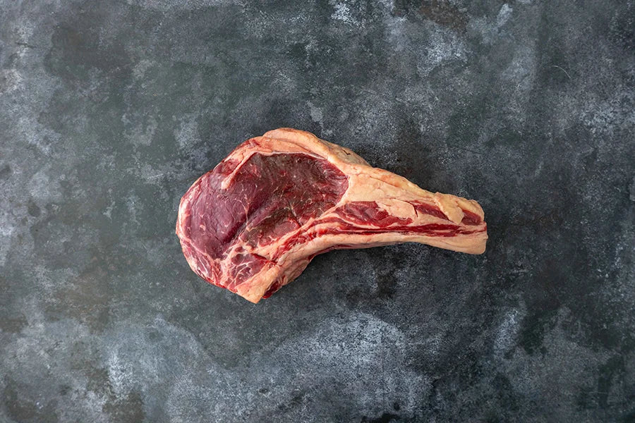 Single Tomahawk Steak on dark marble tabletop