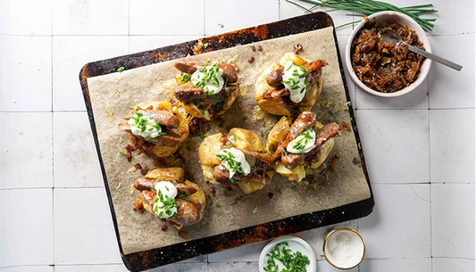 Baked potatoes on tray with sausages
