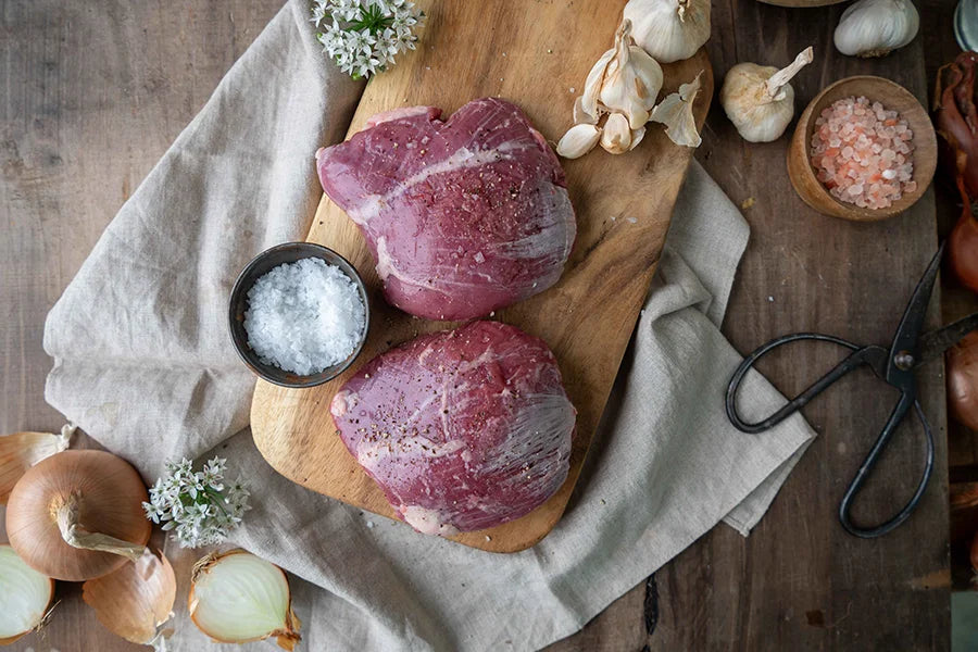 two lamb rumps on chopping board with garlic and salt