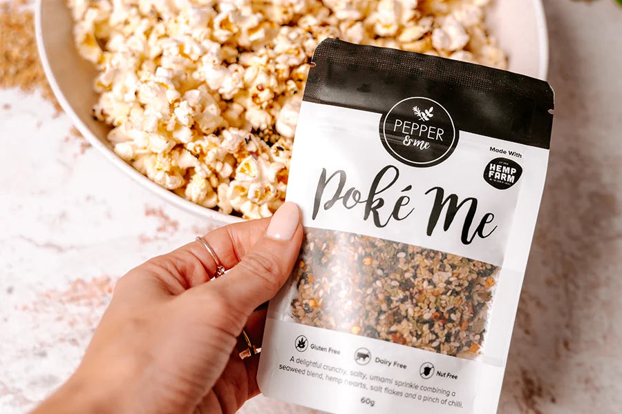 hand holding poke bowl seasoning with popcorn 